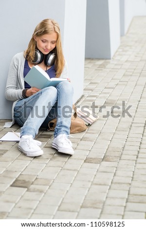 Teenage student girl study siting ground outside university building