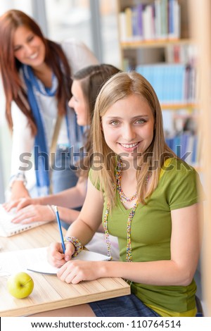 Smiling teenage student girl at study room library high school