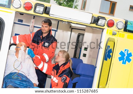Paramedics checking IV drip patient in ambulance treatment aid emergency