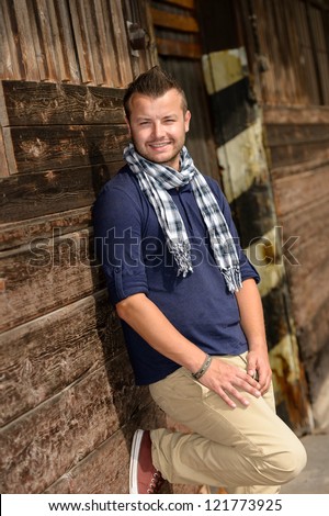Man posing leaning against wooden wall fashion smiling lifestyle leisure