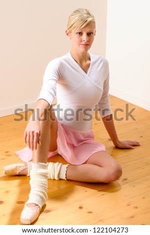 Ballet dancer sitting on the studio floor resting ballerina beautiful