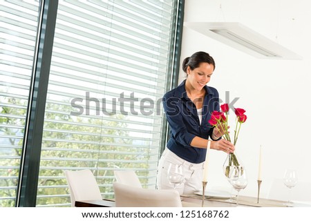 Smiling woman putting red roses dinner room