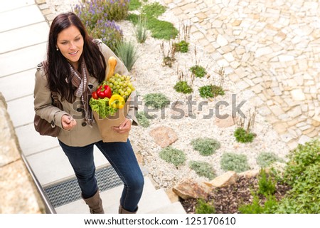 Young woman arriving home groceries shopping smiling garden standing