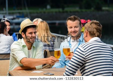 Three male friends relax drinking beer night out restaurant terrace