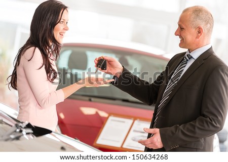 Salesman handing car keys to smiling woman