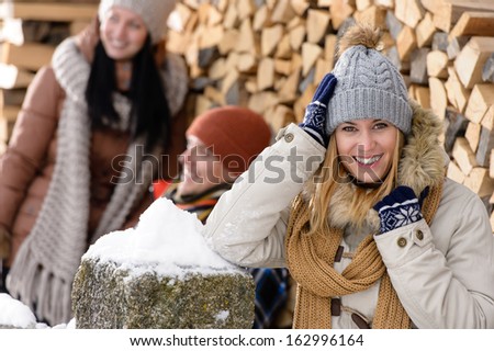 Happy woman with friends smiling outside winter countryside cottage