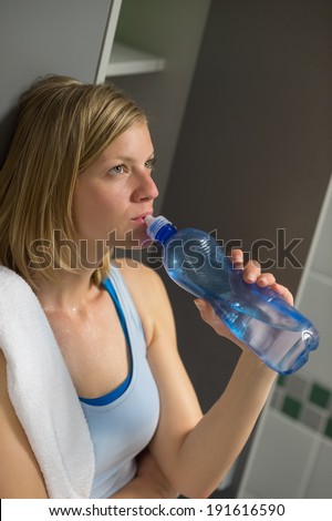 Fit young woman drinking water in locker room at gym