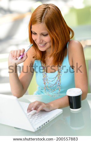 Smiling student girl working on laptop college sitting behind desk