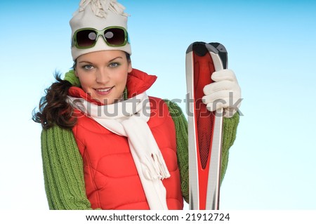 Sexy model in winter outfit with skis on blue background
