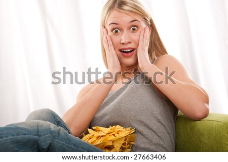 Blond young woman scared in front of TV