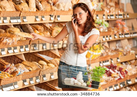 Grocery store: Young woman holding mobile phone and shopping basket