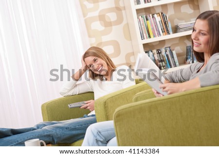 Students - Two female student  relaxing home watching TV and reading book