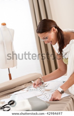 Fashion designer working at studio with dressmakers model and sketches