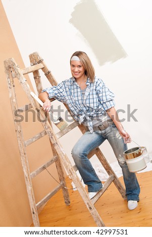 Home improvement: Smiling woman with paint and brush painting wall