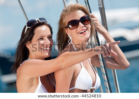 Two attractive smiling woman on sail yacht having fun on sunny day