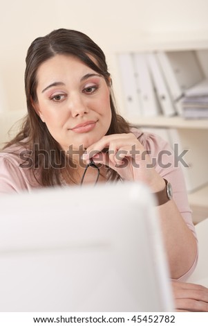 Young businesswoman watching computer screen at office, thinking