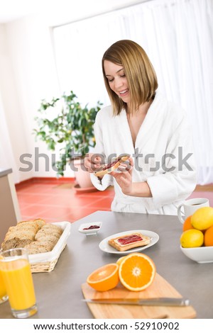 Breakfast - Happy woman with toast and marmalade in bathrobe