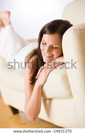 Smiling woman lying down on sofa in lounge