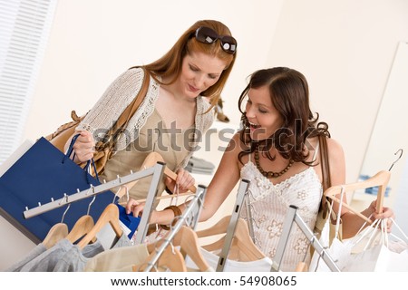 Fashion shopping -  Two happy young woman choose clothes in shop holding shopping bag