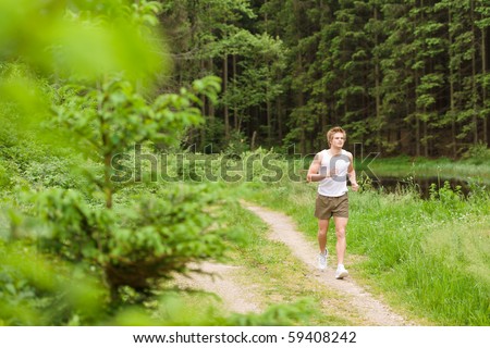 Sportive man jogging in nature by lake in sportive outfit