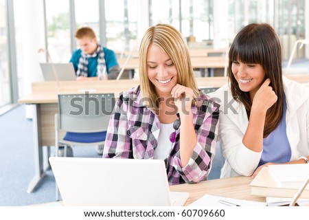 Three high school students in classroom with laptop studying