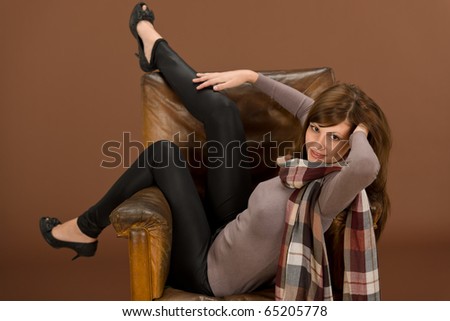 Beautiful brunette Hispanic fashion model on brown leather antique armchair