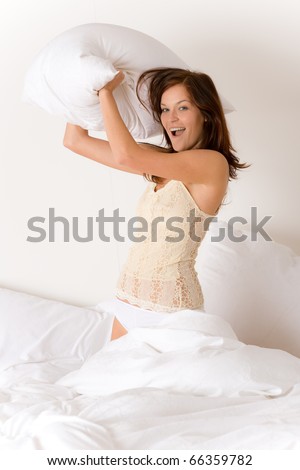 Pillow fight - young woman in bed having fun