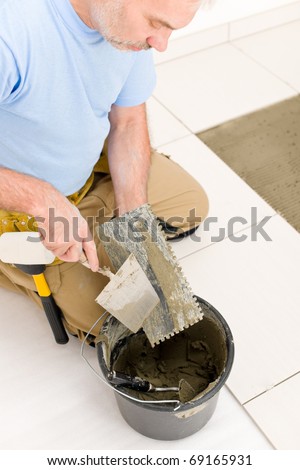 Home improvement, renovation - handyman laying tile, trowel with mortar