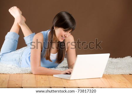 Home study - woman teenager with laptop lying on wooden floor