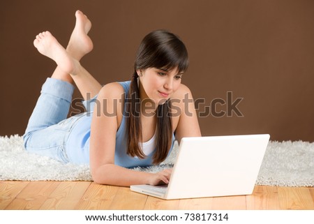 Home study - woman teenager with laptop lying on wooden floor