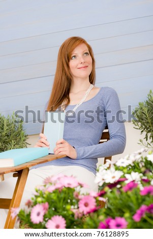 Summer terrace redhead woman relax with book in garden