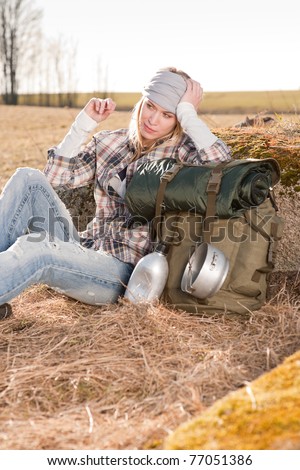 Camping young woman hiking with backpack sitting in countryside