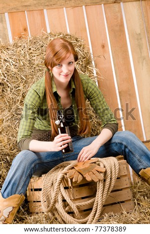 Provocative young cowgirl drink beer in barn country style