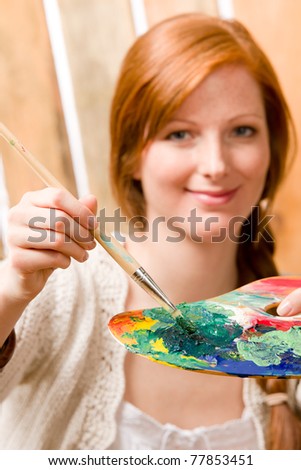 Young romantic red-hair woman painting hold color palette in barn