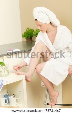 Young student girl polishing her toe nails with pink nail-varnish