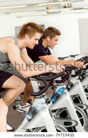 Fitness young man on gym bike indoor cardio exercise