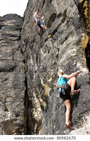 Rock climbing male instructor hold rope blond woman hanging