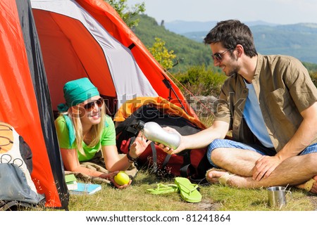 Happy camping couple with tent backpack in sunny countryside
