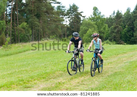 Sport happy couple riding bicycles in countryside meadows