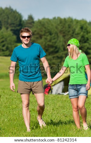 Young camping couple hold hands in summer countryside tent