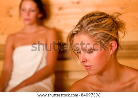 Sauna two healthy beautiful women relaxing sweating covered towels