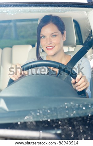 Attractive elegant businesswoman driving luxury new car smiling behind window