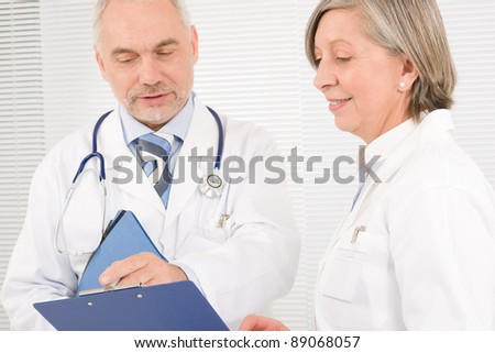 Medical doctor team senior woman and mature man holding folders