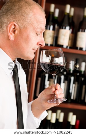 Waiter at bar smell glass of red wine in restaurant