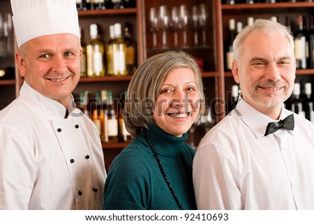 Restaurant manager posing with chef cook and waiter wine bar