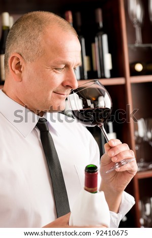 Waiter at bar smell glass of red wine in restaurant