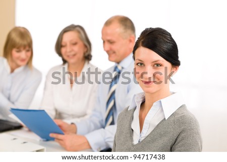 Young executive woman looking camera during meeting with team colleagues
