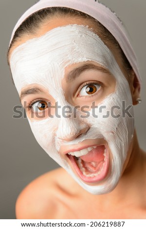 Crazy teenage girl face mask open mouth shouting close-up looking camera