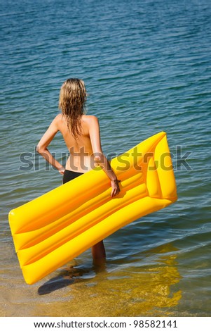 Summer woman by sea water with floating mattress looking forward