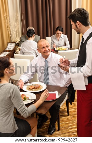 Business people served by waiter enjoy lunch at the restaurant